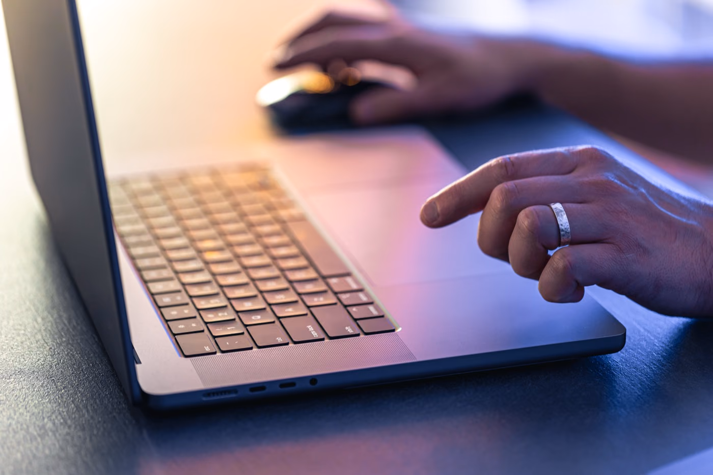 Des mains sur le clavier et la souris d'un ordinateur portable