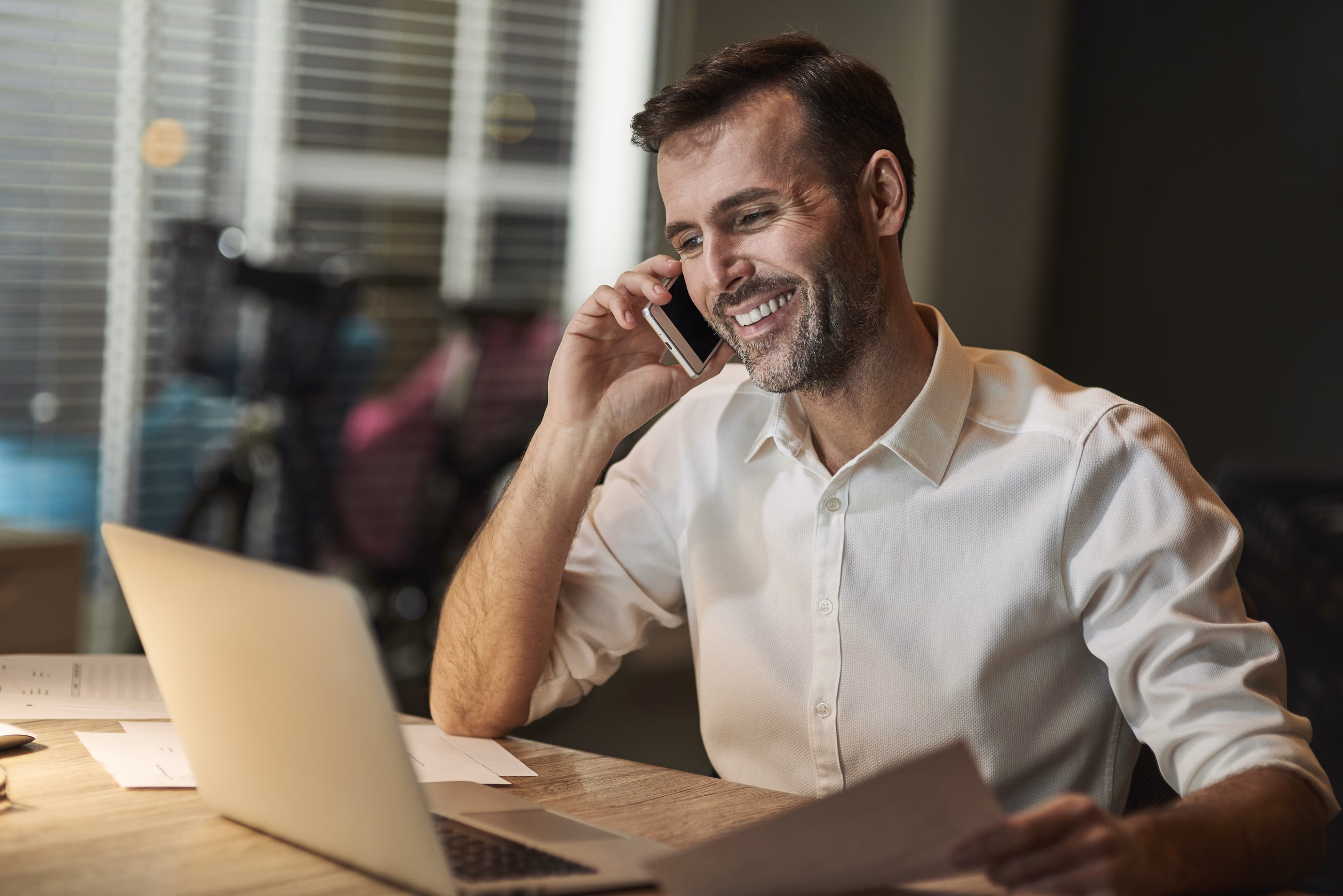 Un conseiller souriant au téléphone, devant son ordinateur portable