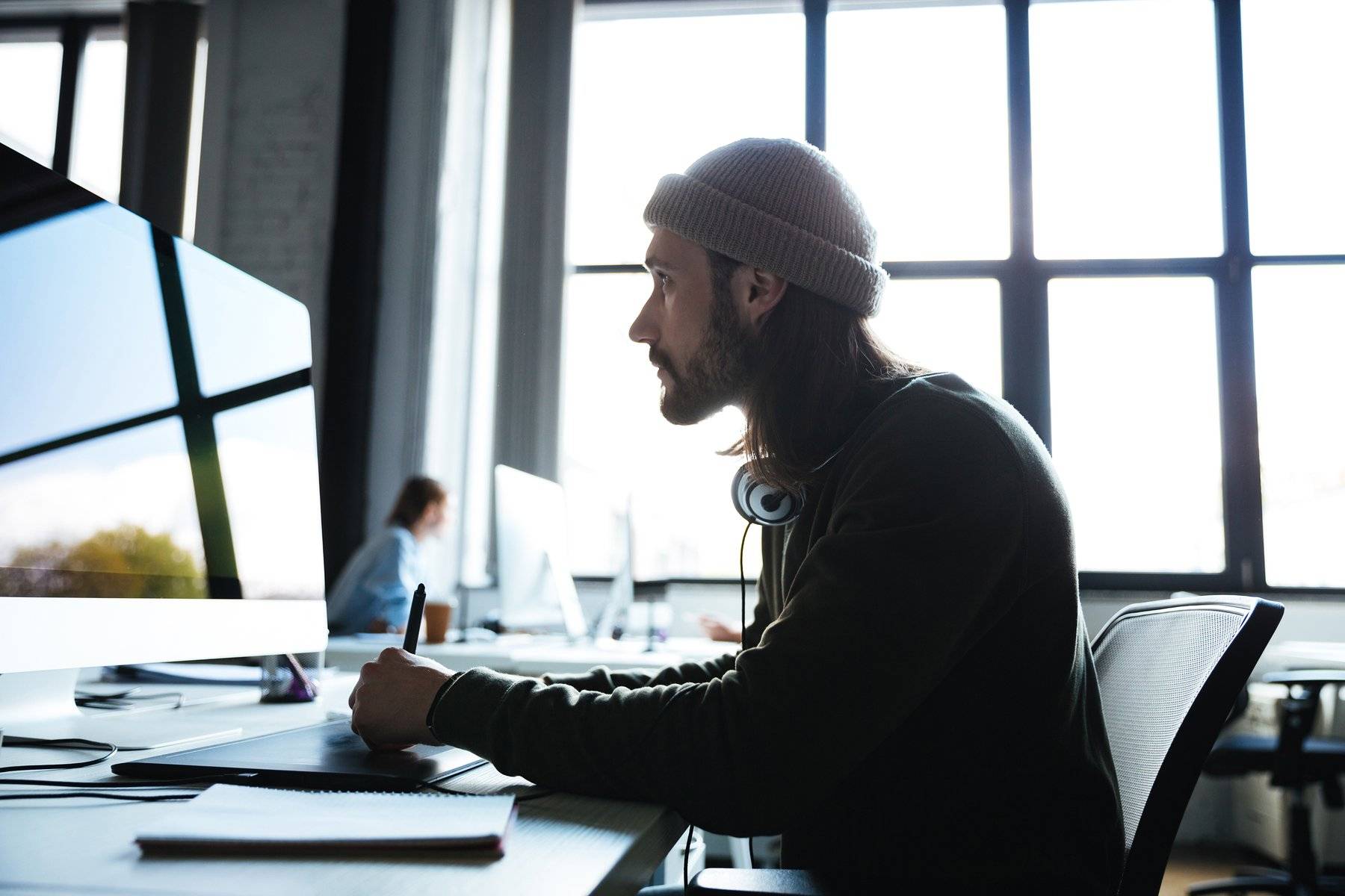 Un webdesigner concentré devant son écran, en espace de coworking