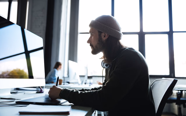 Un webdesigner concentré devant son écran, en espace de coworking