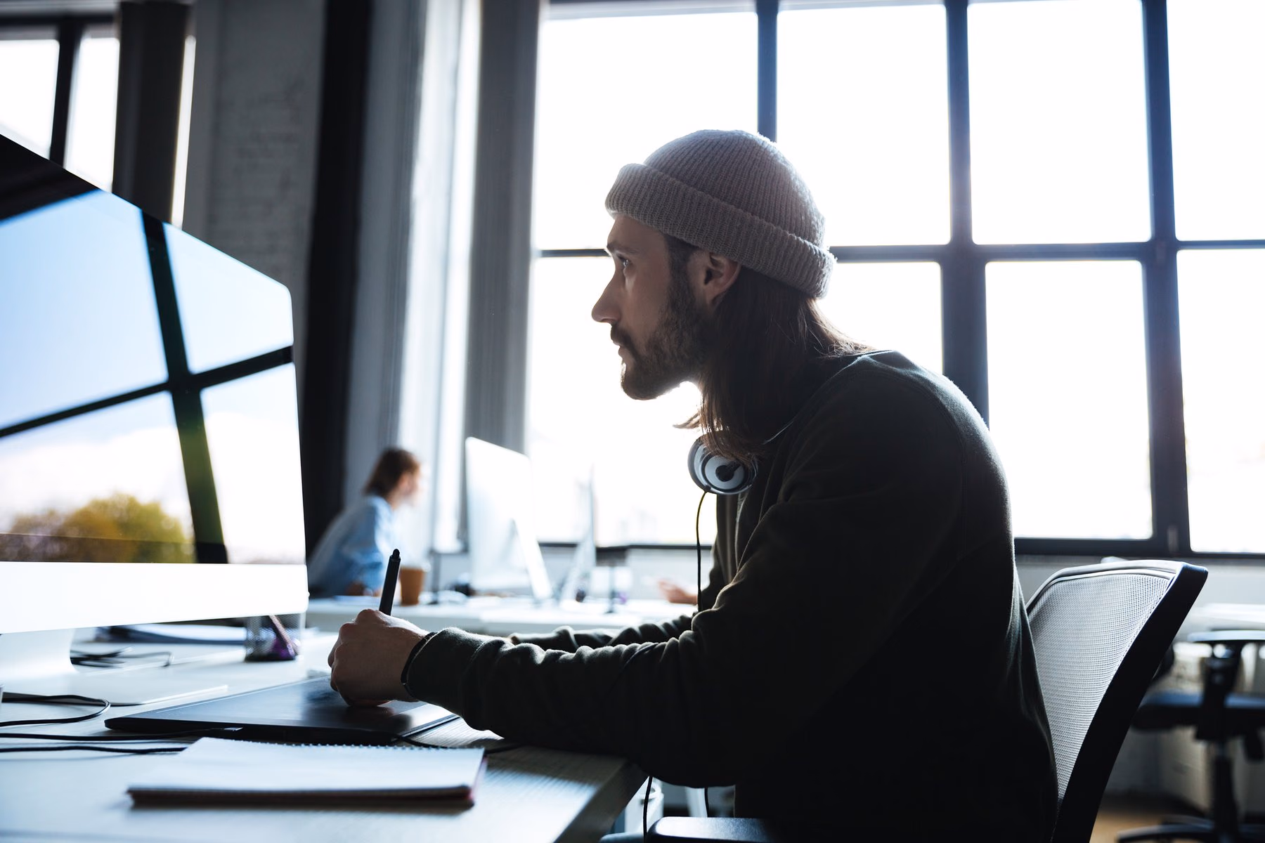 Un webdesigner concentré devant son écran, en espace de coworking
