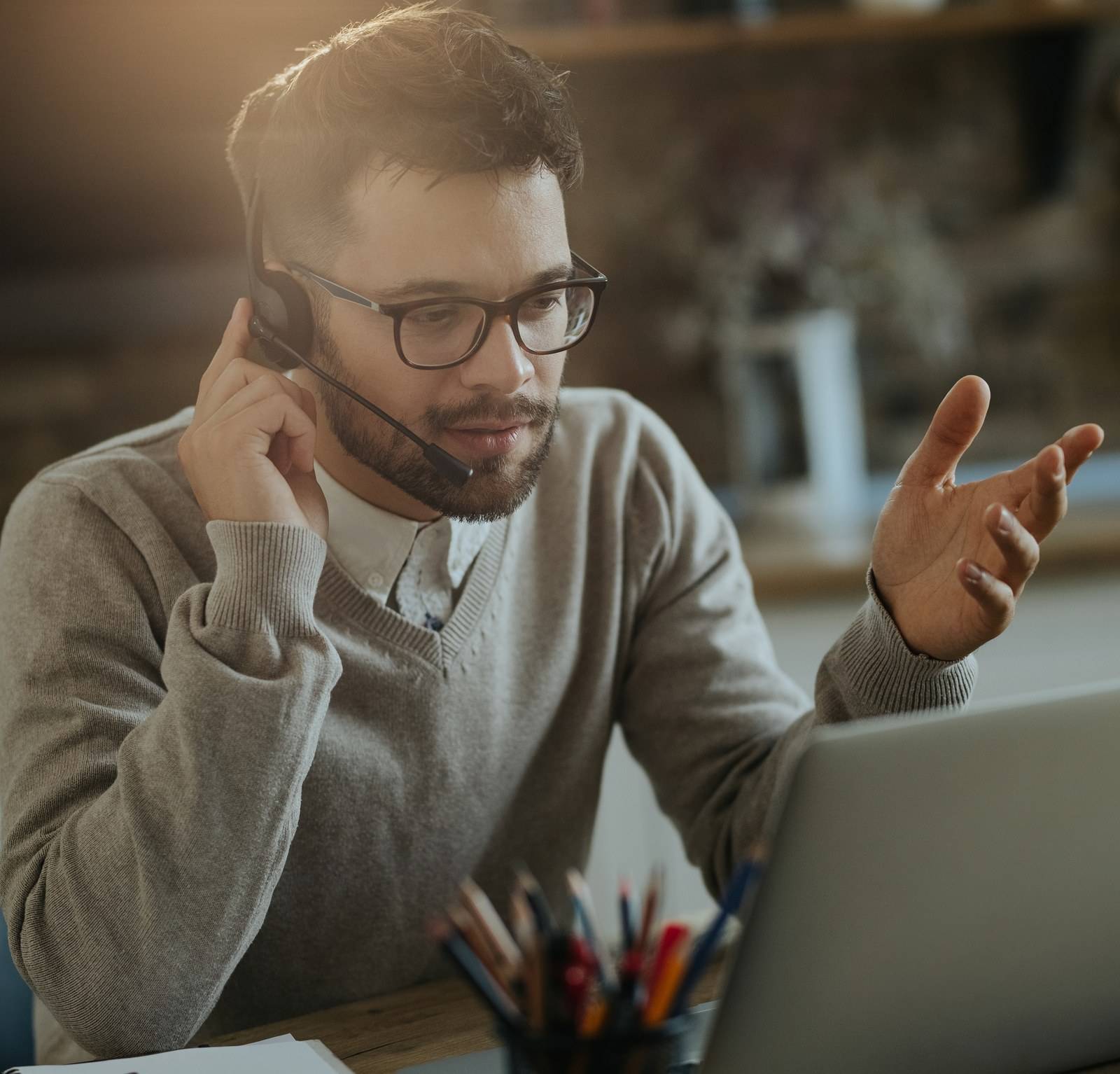 Un coach au casque explique face à son laptop, la main levée