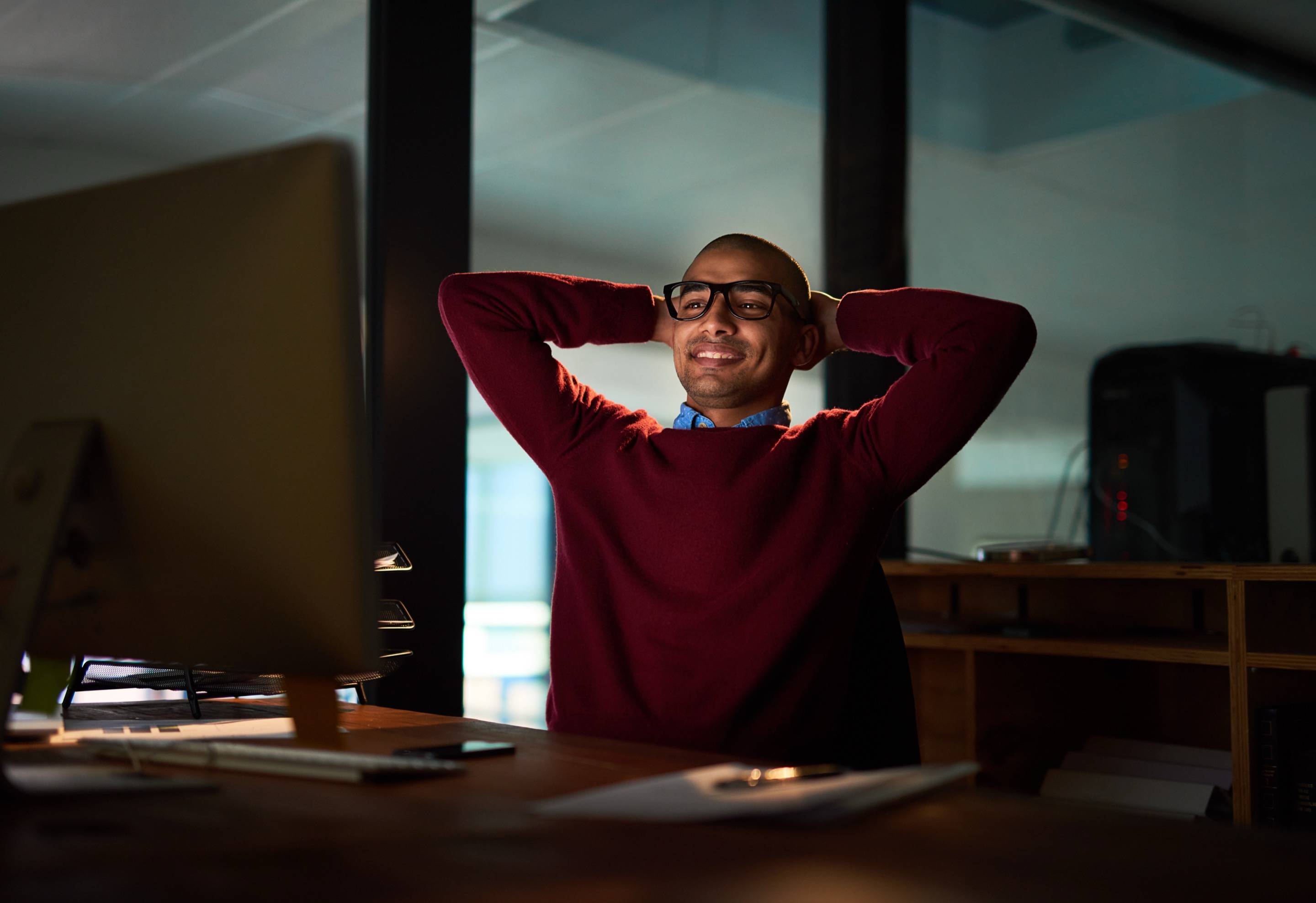 Un webdesigner détendu devant son écran, les mains derrière la tête